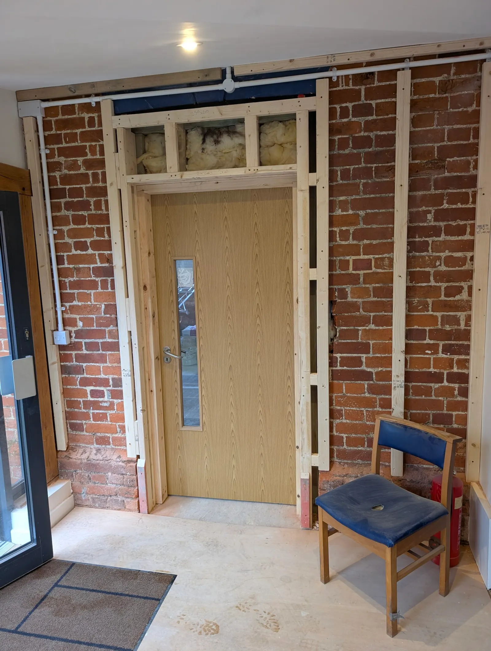 The corridor's new door frame set into the exposed brick wall, ready for plastering