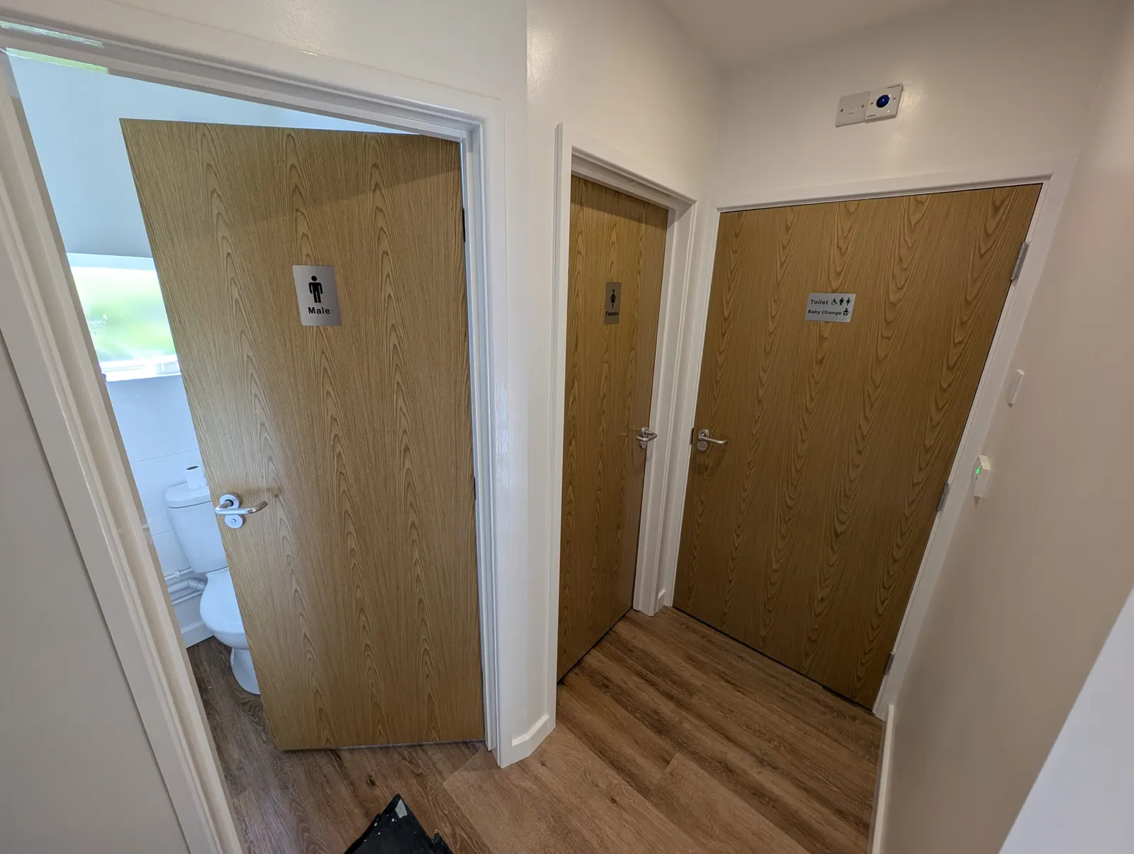 The three new toilet doors, marked Male, Female, and accessible toilet with baby change